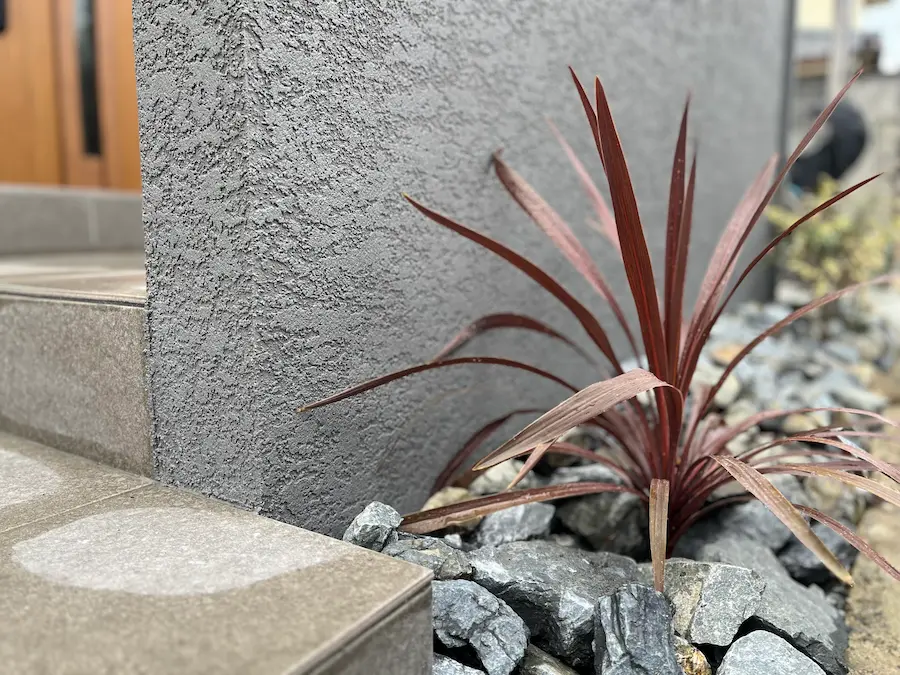 割栗石の隙間から植物が顔を出すロックガーデンと、スタイリッシュな造作門柱