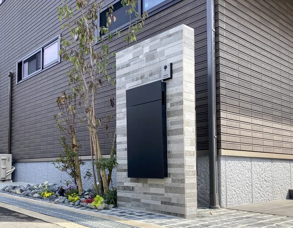 石張り門柱と大型ポストがある新築外構の植栽スペース