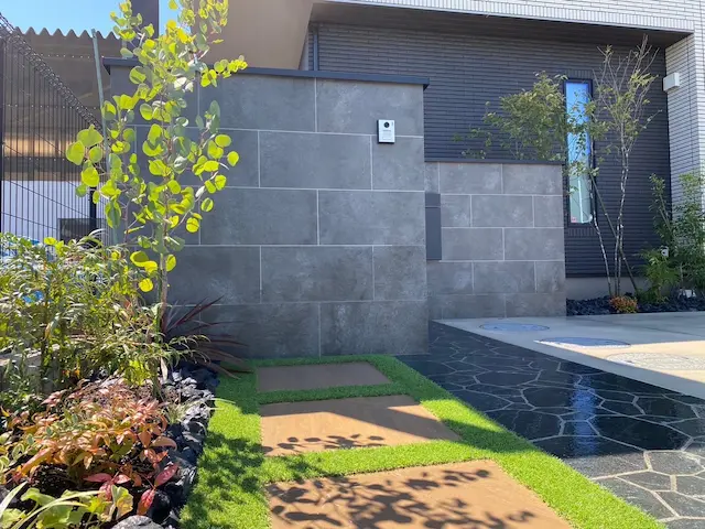 SOTORIE柏逆井のエクステリア施工実績1、船橋市I様邸。グレーのタイル貼りの門柱と、人工芝で縁取られたアプローチがあるモダンな住宅の外構