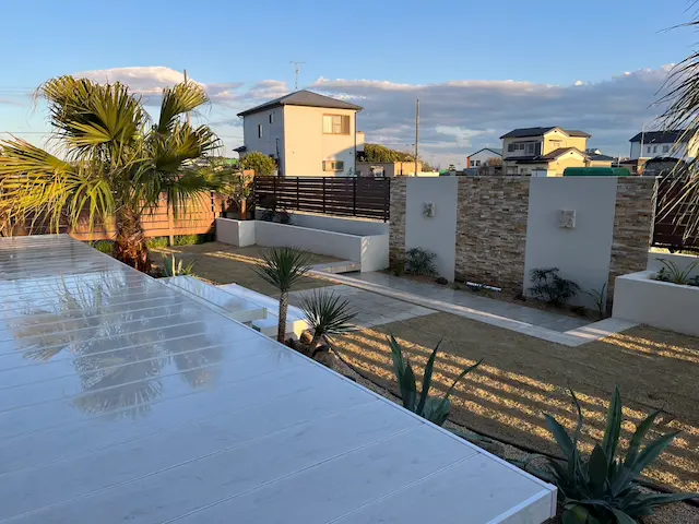 SOTORIE柏逆井のエクステリア施工実績3、市川市A様邸。タイルデッキとヤシの木が配置された、広々としたリゾート風の庭。