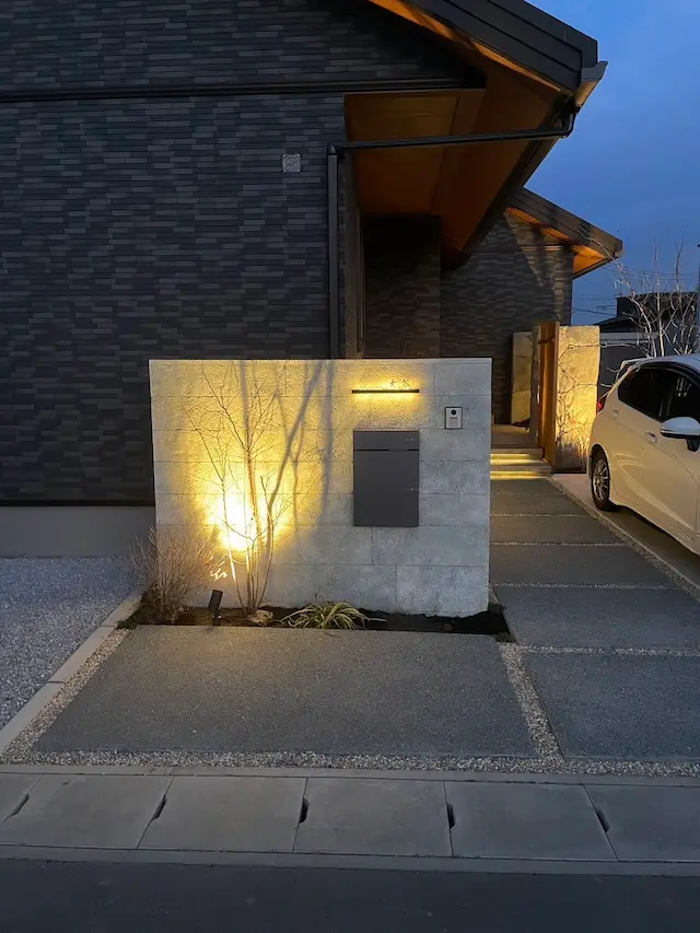 SOTORIE群馬伊勢崎のエクステリア施工実績2、南欧風のテラコッタ色の住宅に合わせた、石積みと漆喰のような風合いのモルタル造形による高い造作門柱。経年変化で一部の石積みが露出したようなデザイン。