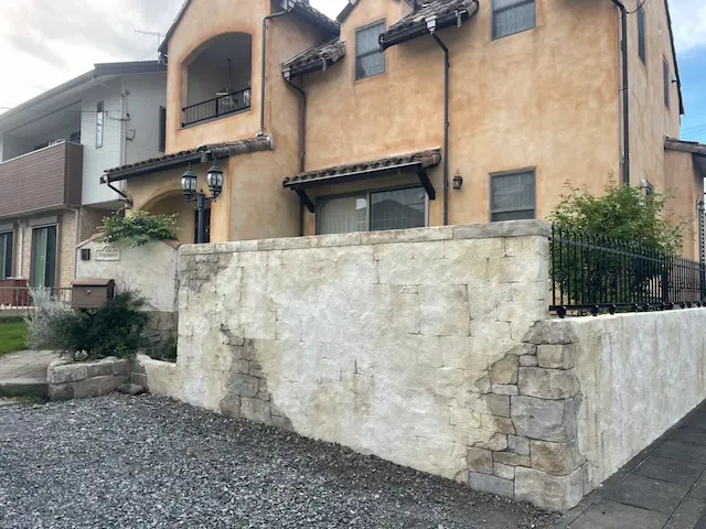 SOTORIE群馬伊勢崎のエクステリア施工実績4、コンクリート打ちっぱなし風の門柱と、木々のシルエットを強調したスポットライトによるライティングデザインのモダン外構の夜景。