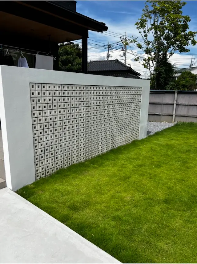 SOTORIE埼玉鶴ヶ島のエクステリア施工実績9、ホワイトの塗り壁にデザインブロックをはめ込んだ、芝生の庭の目隠し塀