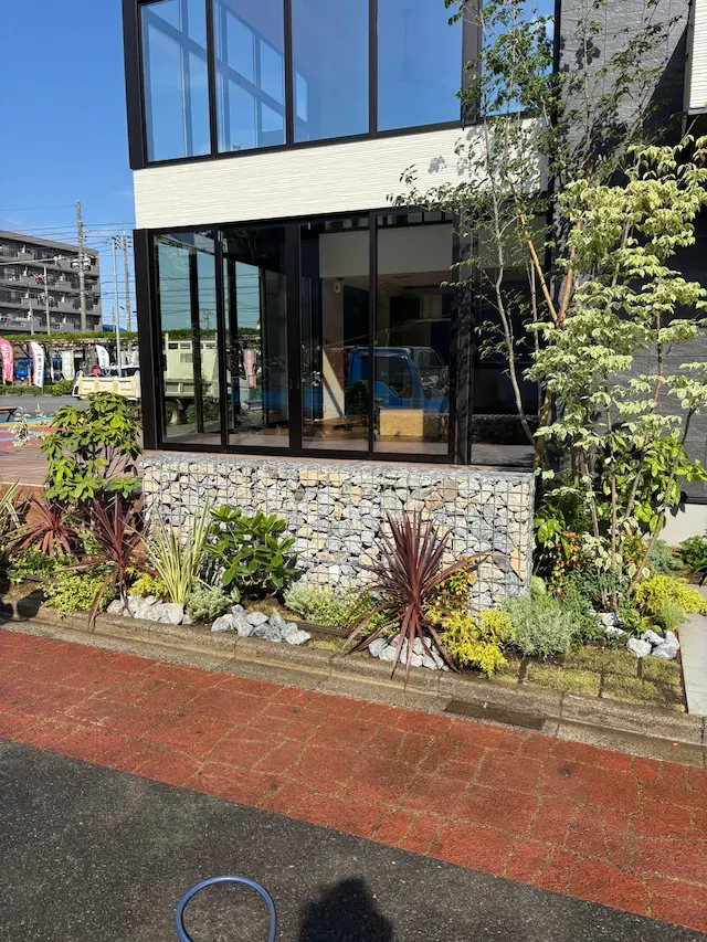 SOTORIE埼玉鶴ヶ島のエクステリア施工実績2、ガビオン(蛇籠)の土留めと鮮やかな植栽がある住宅のファサード