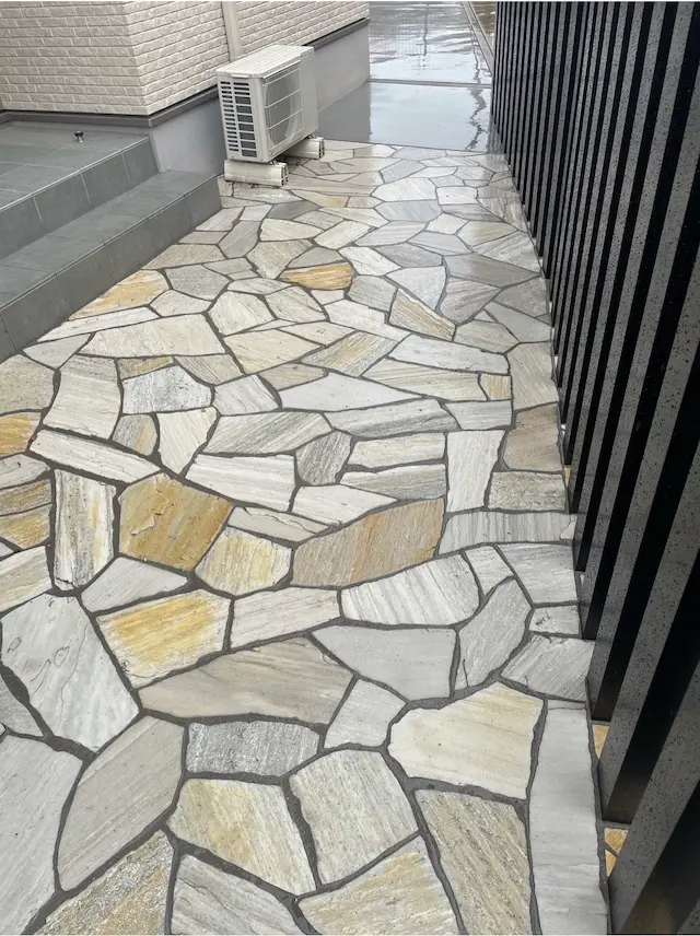 SOTORIE埼玉鶴ヶ島のエクステリア施工実績10、ベージュ系の乱形石を敷き詰めた、建物横の犬走りアプローチ