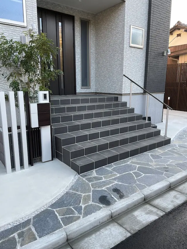 SOTORIE埼玉鶴ヶ島のエクステリア施工実績6、黒いタイル階段と乱形石貼り、機能門柱を組み合わせた玄関ポーチ